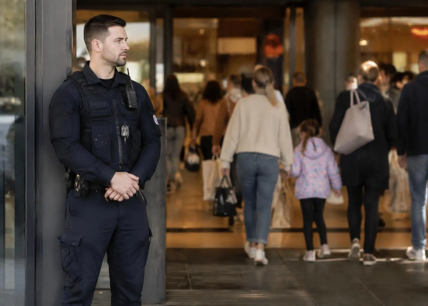 Security officer standing at the entrance of a busy shopping centre